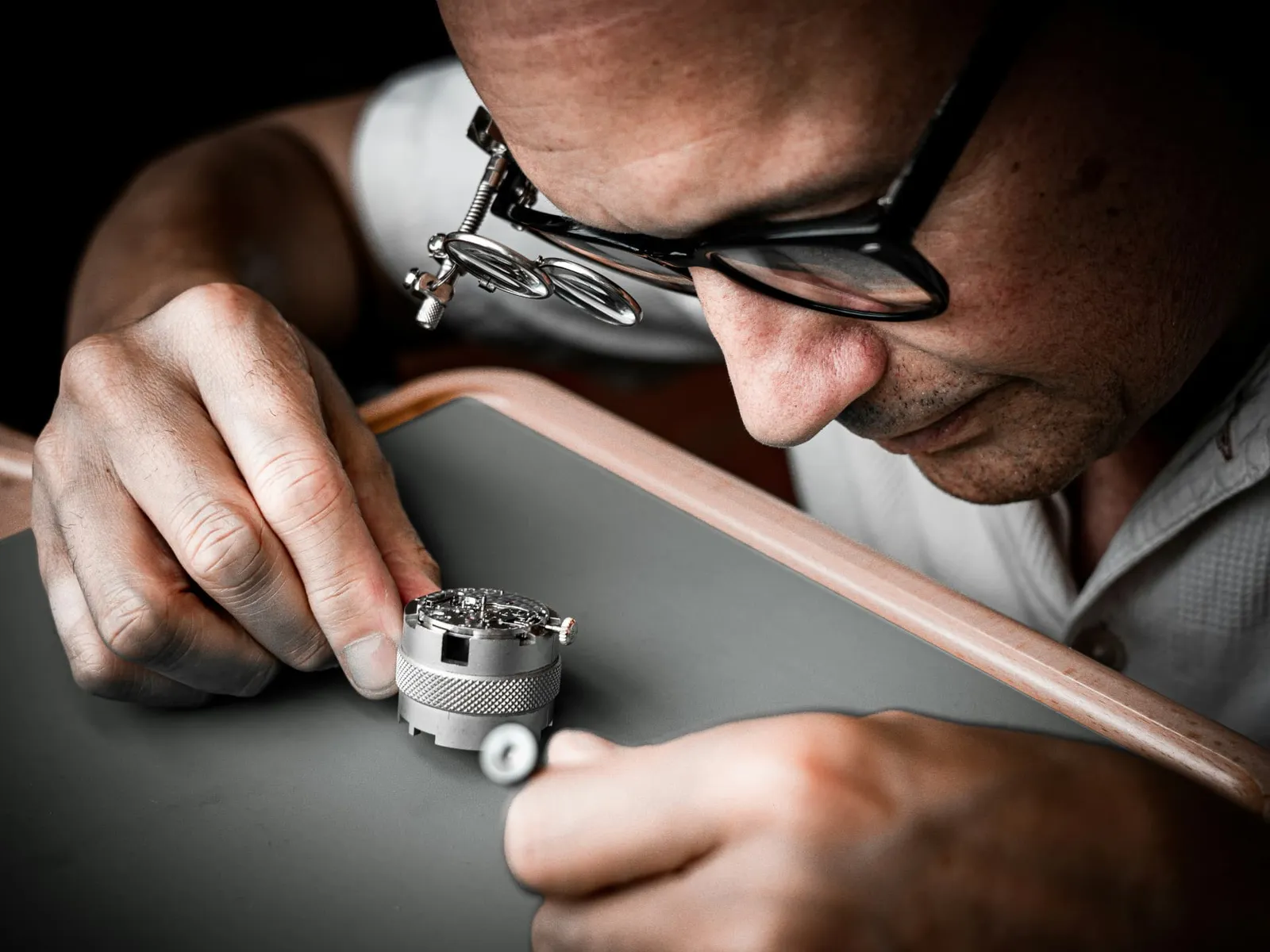Uhrmacher bei filigraner Handarbeit an einem Uhrwerk im Atelier